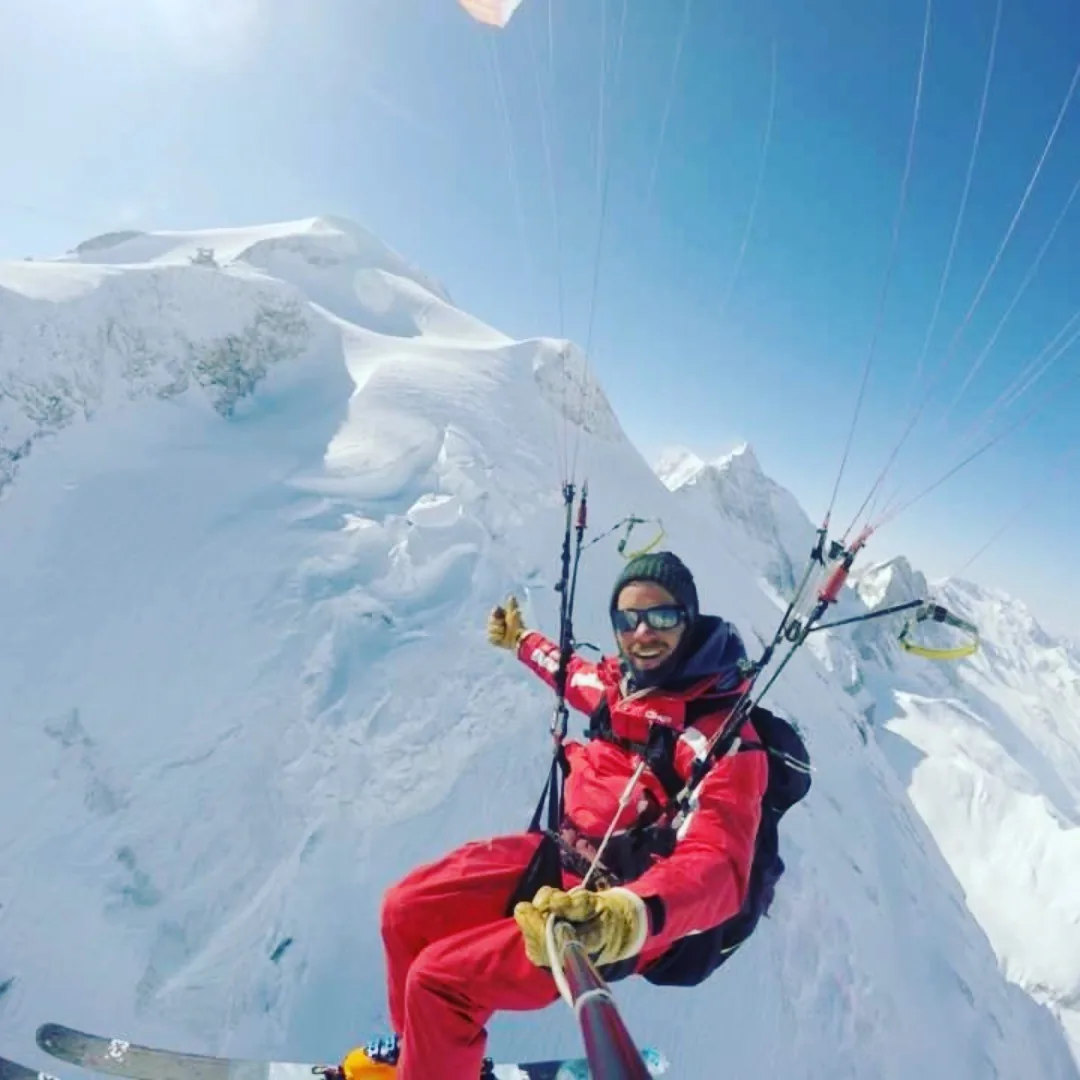Moniteur de parapente en vol au-dessus des crêtes enneigées de Tignes