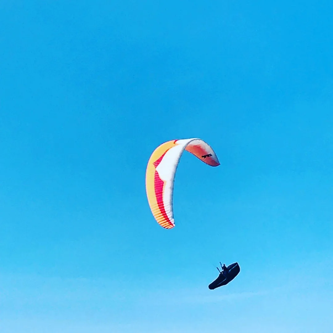 Voile de parapente orange dans le grand ciel bleu de Tignes