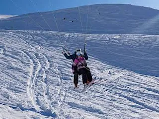 Moniteur et passager en speed riding glissant sur une pente damée